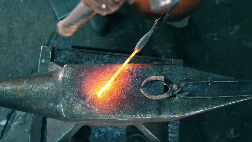 A person works with a hammer, hitting a knife.