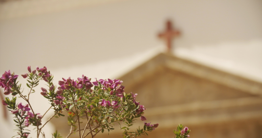 Close-up focus pull of flowers in front of Church cross | Shutterstock HD Video #1035654275