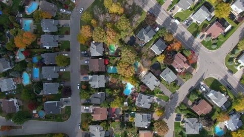 Fall in Montreal, Quebec, Canada, top-down aerial view of residential neighbourhood showing family homes and maple trees changing colour in Autumn season.