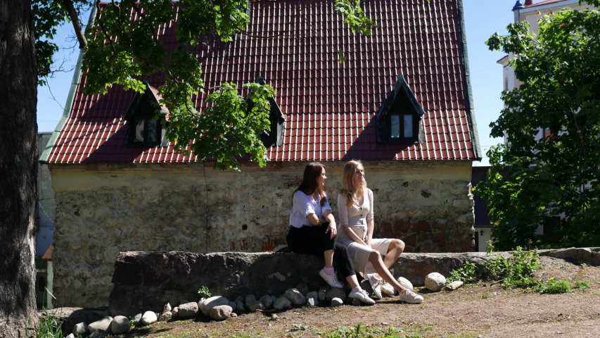 two women chatting while sitting under a tree in the old town