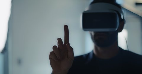 Portrait of a business man using a Virtual Reality headset works and gestures in Augmented Reality.