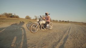 Motorcyclist driving his motorbike on the dirt road during sunset slow motion 