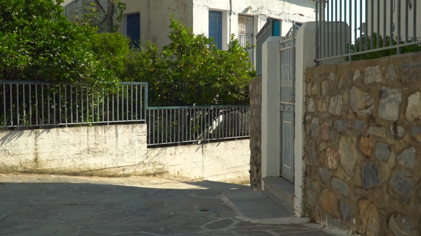 Young woman in summer hat walking through typical Greek Village scene