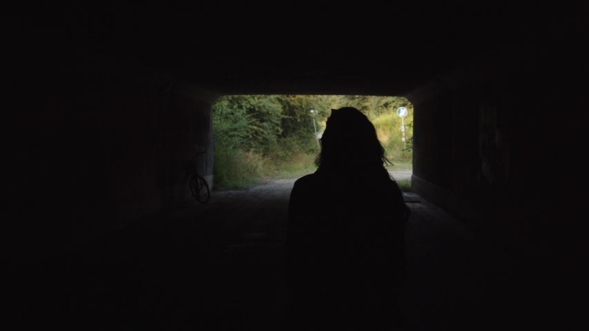 Young European woman walking through a tunnel alone. Camera follow from behind.