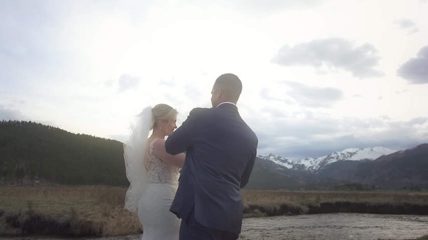 A bride and groom dance and twirl in a mountain field for their first dance for their outdoor elopement