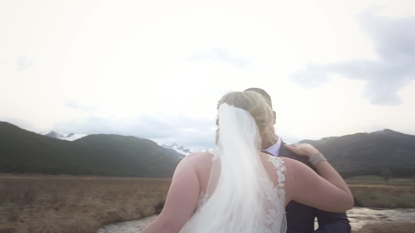 A bride's veil blows in the wind as she dances with her groom at their mountain elopement