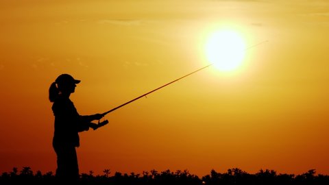 silhouette of Fishman fishing at sunset in summer evening. female fisherman throws fishing tackle.
