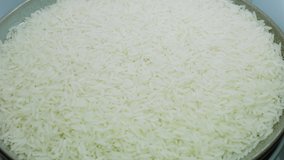 White jasmine rice uncooked in a bowl rotating, detail macro shot. Ideal for videos of cooking, kitchen, cereals, ingredients, rice culture, asian cuisine, restaurants, farms, agriculture and more.