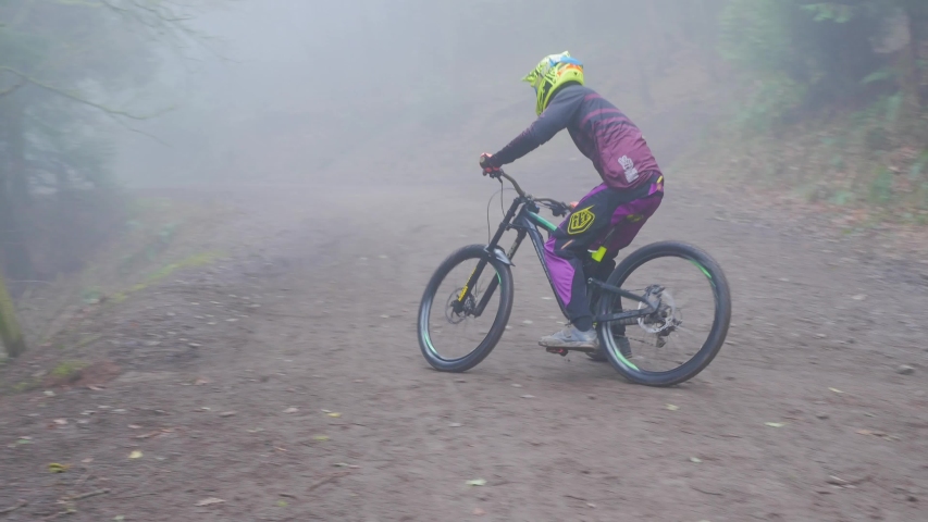 A Mountain Biker Jumps From a small Jump In A Forest.