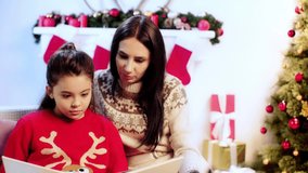 mother and daughter reading book on christmas