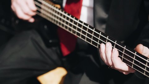 Bassist plays bass guitar. Close-up of his hand and strings. rock band.