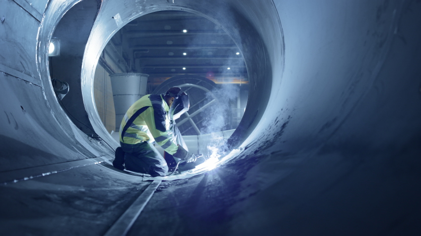 Professional Heavy Industry Welder Working Inside Pipe, Wears Helmet and Starts Welding. Construction of the Oil, Natural Gas and Fuels Transport Pipeline. Industrial Manufacturing Factory.Slow Motion | Shutterstock HD Video #1035704201