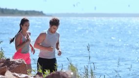 young man and woman in sportswear running on seaside together