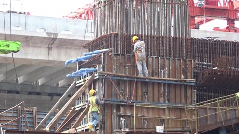 KUALA LUMPUR , KUALA LUMPUR / Malaysia - 04 15 2019: Construction workers working at height installing reinforcement bar and form work at the construction site.