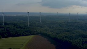 Aerial view of wind turbines close to Berlichingen in Germany. Pan to the left from behind the turbines.