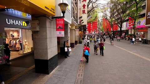 GUANGZHOU, CHINA - MARCH 14, 2018: Shopping district pedestrian street, famous Beijing Lu, panning camera motion across alley. Unidentified Asian people stroll by road, many fashion stores around