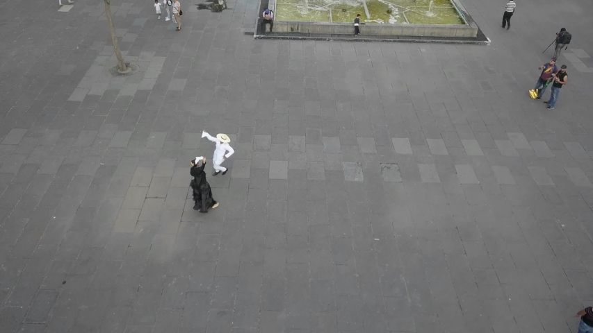 beautiful scene of two people dancing in a central plaza/ aerial shot