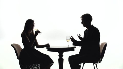 Silhouettes of man and woman on a date on a white background in studio