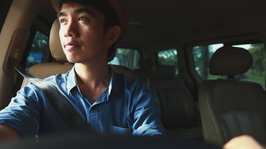 Medium shot of Happy Asian man driving a car and looking outside | Shutterstock HD Video #1035743924