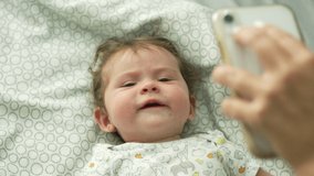 Slow motion of baby sneezing while looking up at cell phone