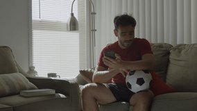 Slow motion of soccer fan kissing a soccer ball and holding mobile phone