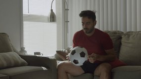 Slow motion of man playing with soccer ball at home gets up and leaves