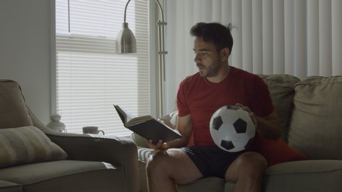Man holding soccer ball, reading about plays in book and imagining a goal