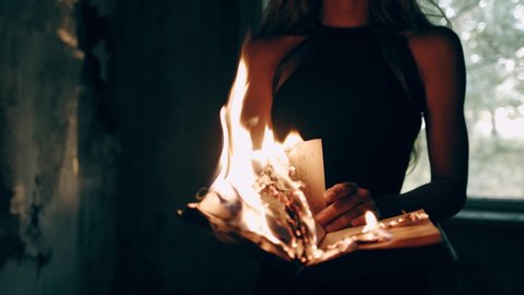 Old vintage book burns with fire in the hands of a woman in a dress स्टॉक व्हिडिओ