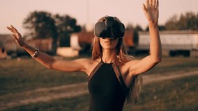 Young beautiful woman is testing 3d virtual reality glasses outdoor at sunset background. Attractive girl is using virtual reality headset and having VR experience