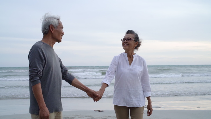 Asian couple senior elder retire resting relax holding hand walking at sunset beach honeymoon family together happiness people lifestyle, Slow motion footage