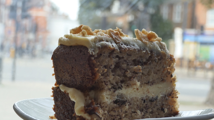 A slice of walnut cake by a window in a cafe.