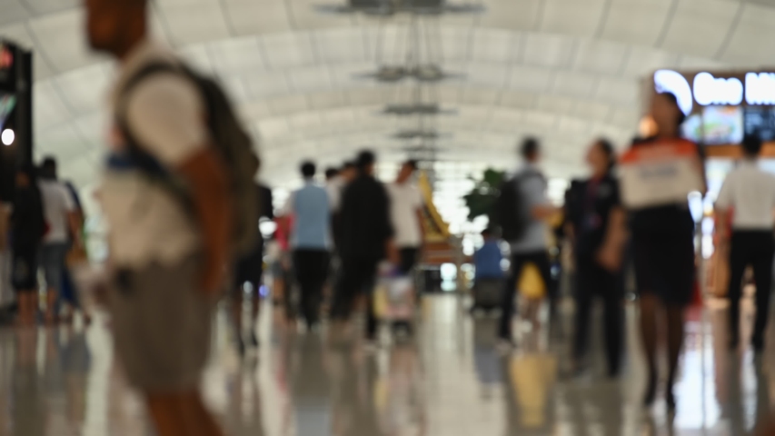 Blur background time lapse 4K UHD footage of crowd passengers or travelers commuting in international airport walkway walking and shopping before go to their flight terminal gate.