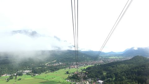 View of Garmisch-Partenkirchen and ride with the cable car into the clouds and over the clouds.