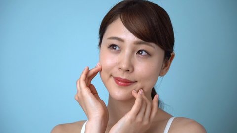 footage of attractive asian woman skincare on blue background