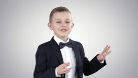 Little boy in formal outfit talking and smiling on gradient background.