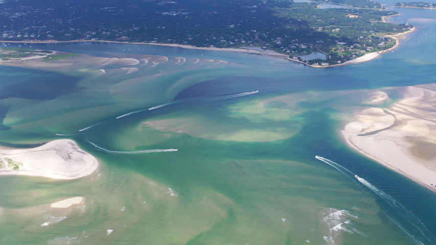 Small boats navigate a channel between sand islands on Cape Cod, Massachusetts. This beautiful area of New England, not too far from Boston, is a popular summer vacation destination.