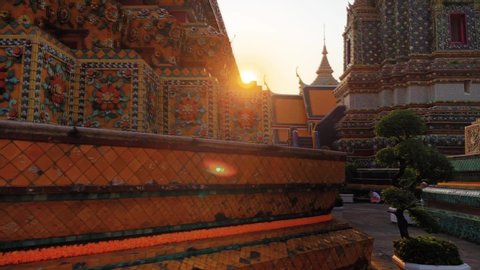 Scene of the pagodas of Wat Pho in Bangkok basking in warm golden sunset.