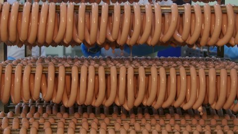 Fresh sausages are placed on racks in a meat processing factory