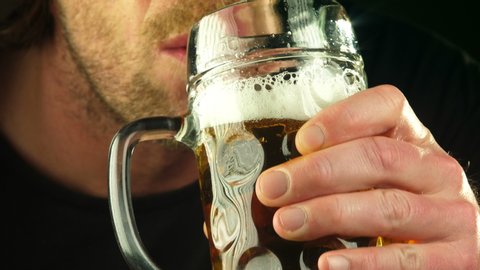 Man drinking alcoholic drink from glass mug of beer