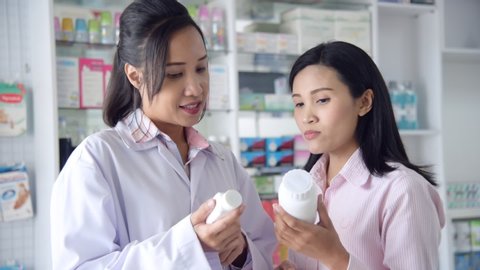 Asian pharmacist gives advice to patient about medicine in drugstore