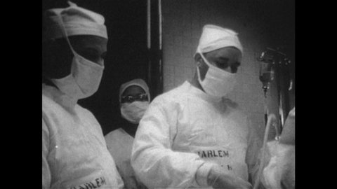 1950s: UNITED STATES: Harlem hospital outfit. Surgeon in operating theatre. Medics in operating room during surgery.