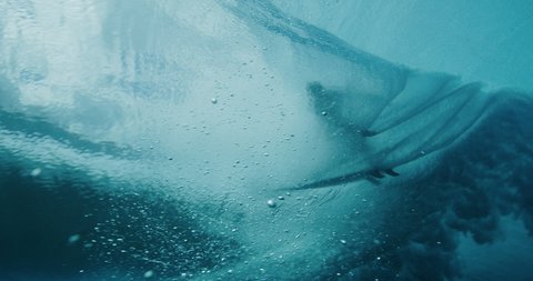 Underwater shot of the silhouette of a surfer getting barreled, amazing surf cinematography