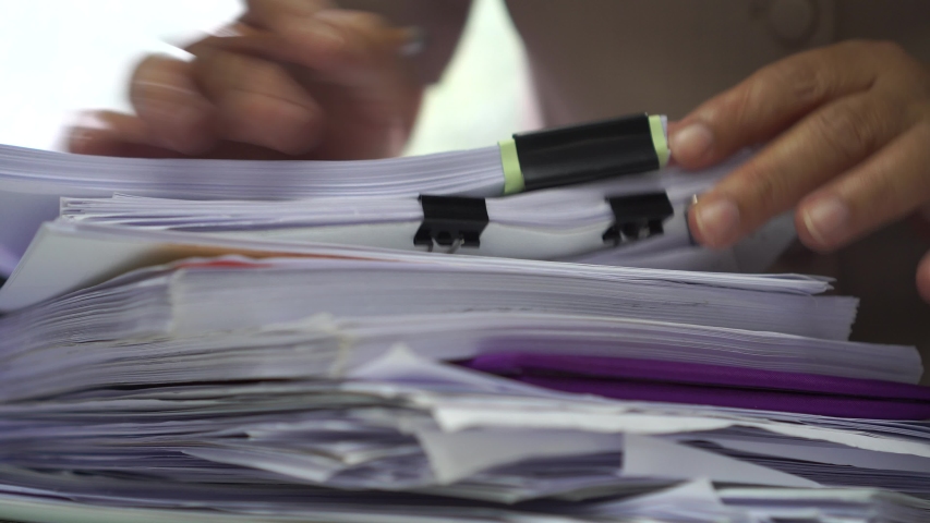 Businessman hands working in stacks of paper files for searching information on work desk office, business report papers,piles of unfinished documents achieves with clips indoor,Business concept, a Business & Finance Video by smolaw