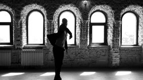 Ballet dancer practicing ballet dance in the studio. Slow motion stylish male ballet dancer in black suit is dancing. Black and white.