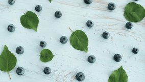 Fresh sweet blueberry with green leaves on wood texture surface. Close up 4k footage. Top view.