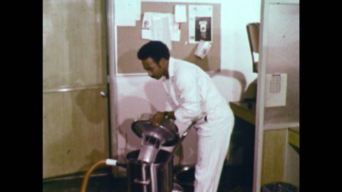 1970s: UNITED STATES: wet and dry vacuum machine. Man removes dust filter machine from vacuum. Float valve on vacuum. Man hoovers up suds from floor. Man removes filter bag for vacuuming of liquids.