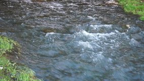 Water stream flows across the stones. River flowing close up.