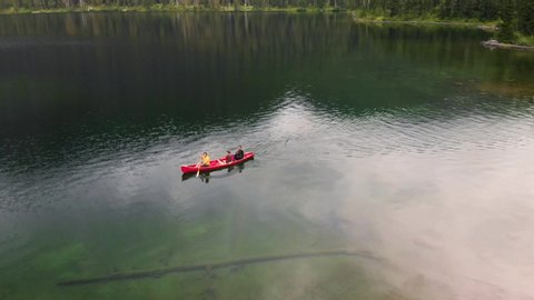 Aerial view of three people in a canoe on a lake - 4k 30fps