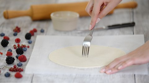 Pricking puff pastry sheet with fork. Making Puff Pastry Cake