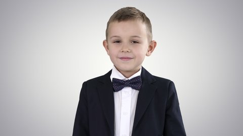 Smiling little boy in formal clothes standing on gradient background.